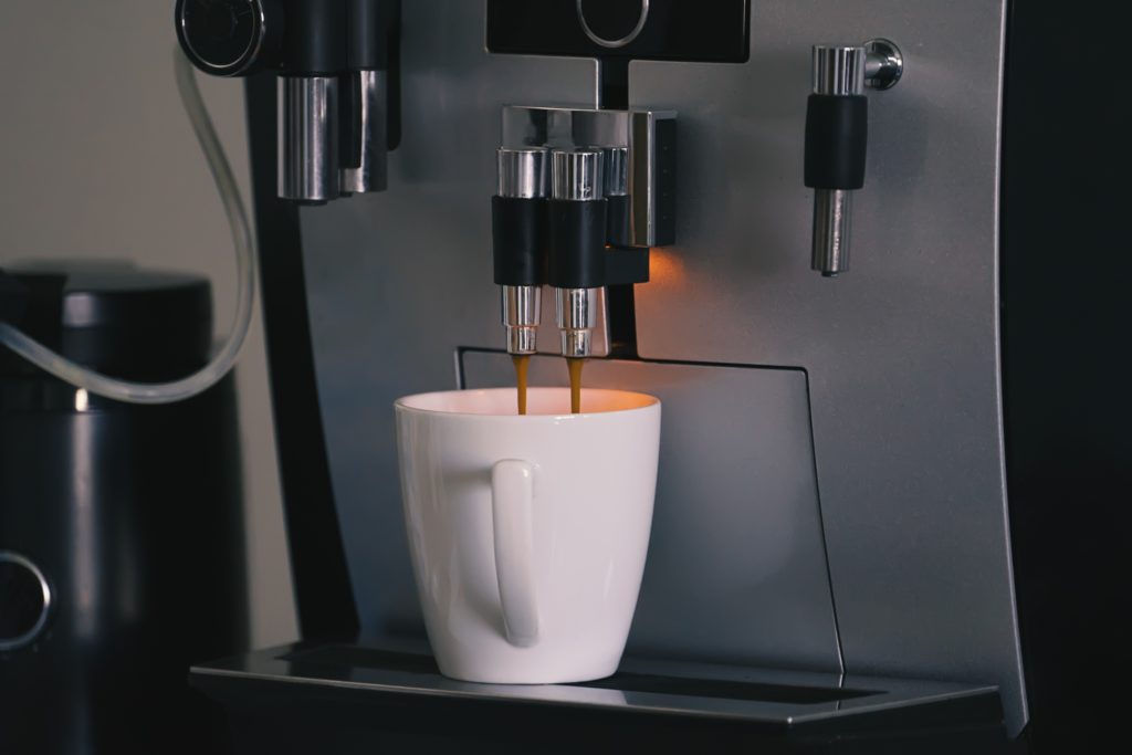 Ein cremiger Espresso wird aus dem Kaffeevollautomaten gezogen.